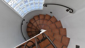 Escadaria em espiral com teto de vidro e corrimãos de metal.