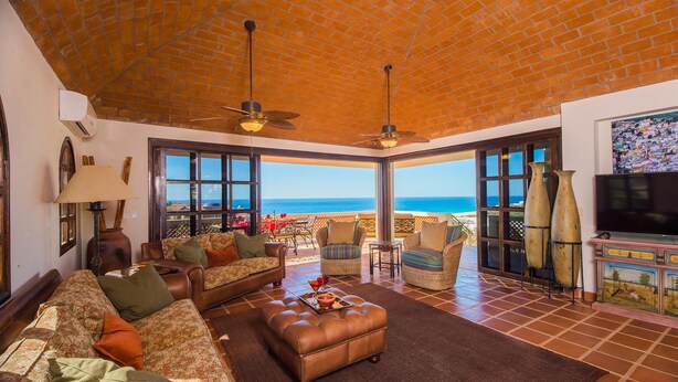Un vaste espace de vie avec vue sur la mer, aménagé avec des canapés, des fauteuils et une table basse.