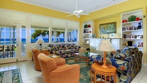 A living room with a sofa, armchairs, and a coffee table. There are bookshelves with books and decorative items.