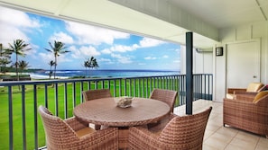 Enjoy ocean views from this balcony with a table and wicker seating.