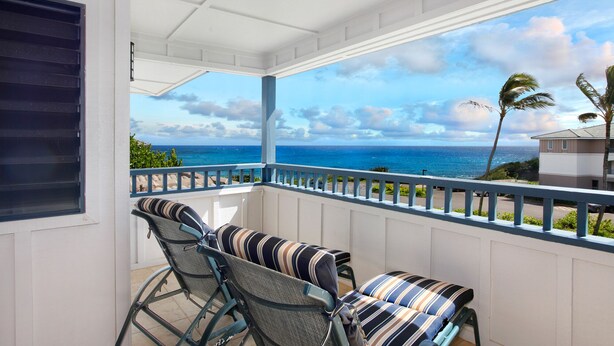 A balcony with a view of the ocean and palm trees.