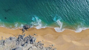 A rocky beach with clear turquoise water and a sandy shore.