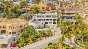 Una zona residencial costera con casas modernas, un camino sinuoso y abundante vegetación.