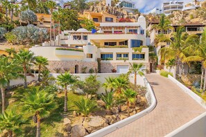 A hillside residential area with modern multi-story buildings, a paved pathway, and tropical vegetation.