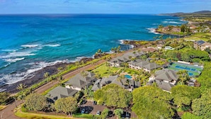 A coastal residential area with houses, a tennis court, and a view of the ocean.
