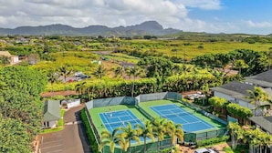 A tennis court surrounded by lush greenery and residential buildings.