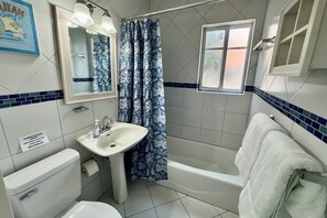 Een bad/douchecombinatie, een haardroger, handdoeken, zeep