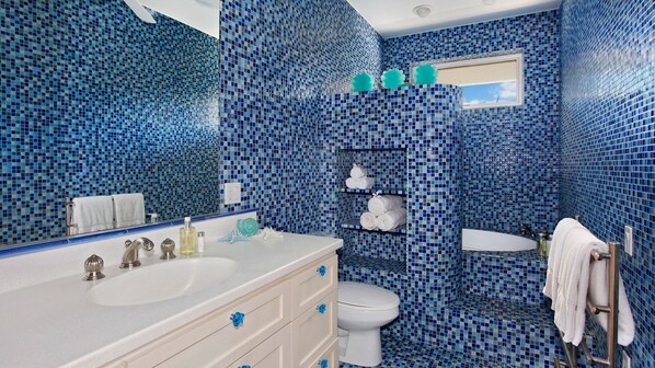 Un baño con mosaicos azules, un lavabo blanco, un inodoro y una zona de ducha.