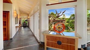 A hallway with a wooden bench, a glass table, and a view of a tropical garden.