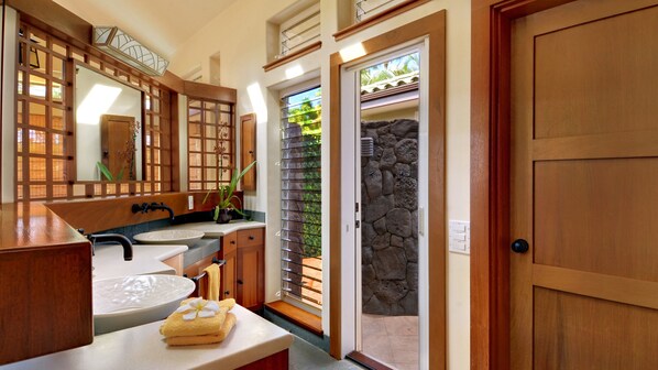 A bathroom with a wooden vanity, a round sink, and a large mirror.