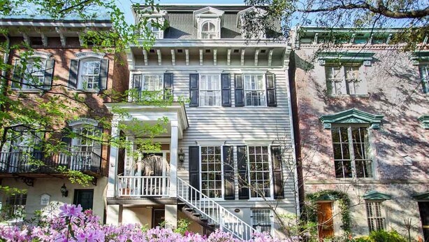 Una hilera de casas adosadas de estilo victoriano con varios pisos, balcones y grandes ventanales.