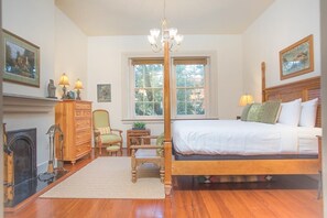 Une chambre à coucher avec un lit à baldaquin, une cheminée, un lustre et une grande fenêtre.