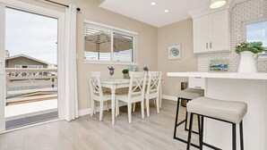 Una cocina moderna con comedor, que cuenta con un amplio ventanal, muebles blancos y vistas al exterior.