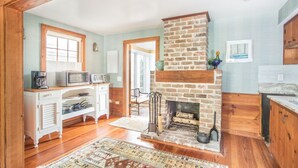 A cozy kitchen with a brick fireplace, wooden cabinets, and a dining area with a table and chairs.