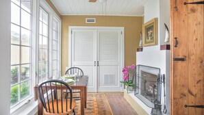 A dining area with a table set for two, a ceiling fan, a fireplace, and a wooden door.