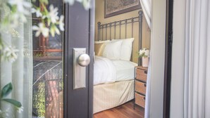 A bedroom with a bed, a nightstand, and a window with a view of a balcony. - Intimate Studio Hideaway Perfect for Couples by Lucky Savannah (Savannah)