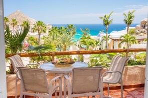 Ein Balkon mit Tisch und Stühlen mit Blick auf einen Strand und Palmen.