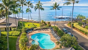 A resort with a swimming pool, lounge chairs, and a view of the ocean.