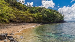 A beach with clear water, rocky shore, and lush greenery. - Family house near Hanalei with ocean views (Princeville)