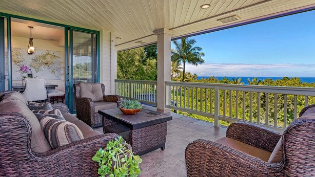 A covered outdoor seating area with wicker furniture, a dining table, and a view of the ocean. - Family house near Hanalei with ocean views (Princeville)