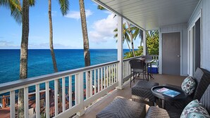 A covered outdoor area with wicker furniture, a table, and a view of the ocean. - Poipu Palms #203 By Parrish Kauai: pristine, updated oceanfront gem w/ sunsets & (Koloa)
