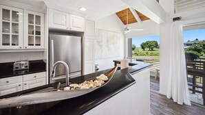 Una cocina moderna con armarios blancos, un refrigerador de acero inoxidable y una encimera negra.
