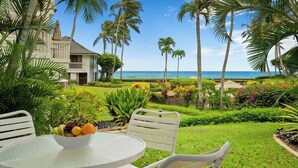 A tropical resort with a view of the ocean, a dining area with a fruit bowl, and lush greenery. - Poipu Kapili 33 By Parrish Kauai - great for honeymoons! (Koloa)