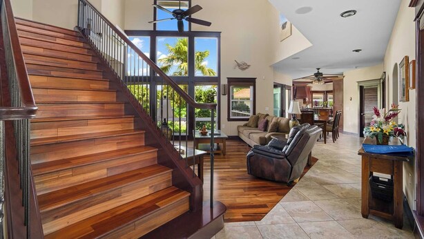 Un salón espacioso con escalera de madera, zona de comedor y vistas al exterior.