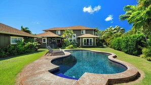Una propiedad residencial con piscina, terraza cubierta y césped bien cuidado.