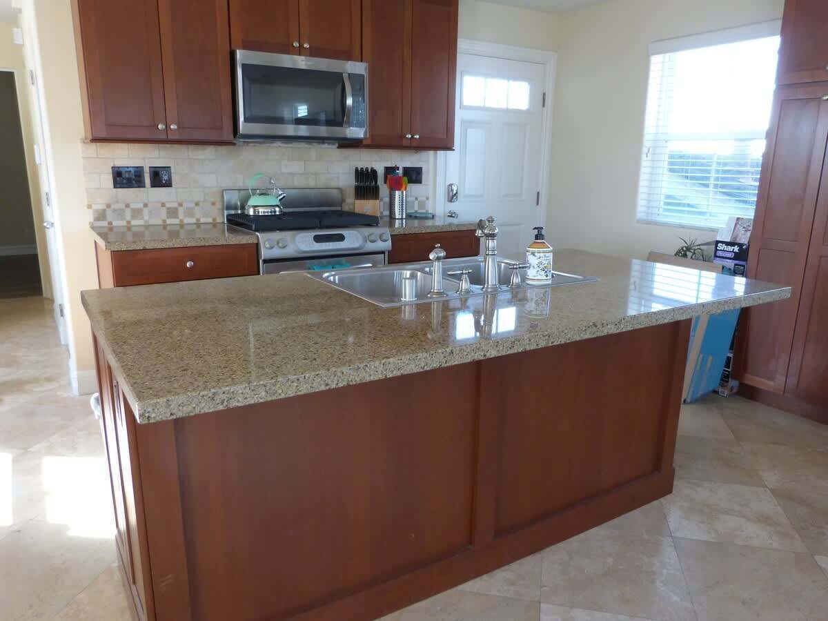 A kitchen with wooden cabinets, a granite countertop, stainless steel appliances, and a window providing natural light.