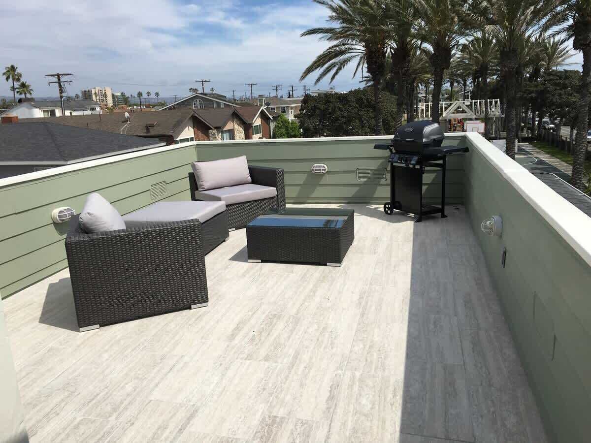 Une terrasse sur le toit, aménagée avec des meubles en osier, un barbecue et offrant une vue sur le quartier.