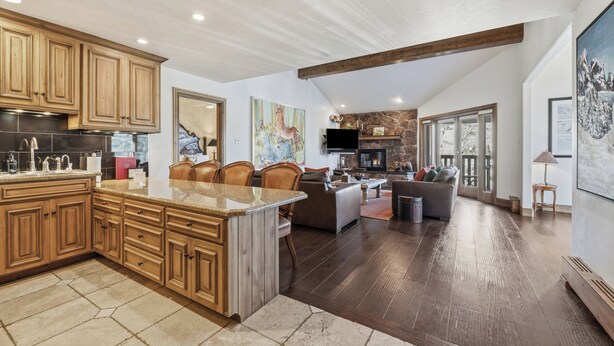 A spacious kitchen with wooden cabinets, a large island, and a stone fireplace. - Luxury Penthouse w Amazing Mountain Views, W404 (Vail)