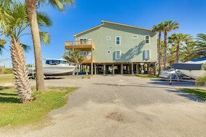 A two-story building with a balcony, surrounded by palm trees and parked boats. - Water View Dauphin Island Condo w/ Boat Slips (Dauphin Island)