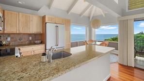 Una cucina moderna con una grande isola, mobili in legno e vista sull'oceano.