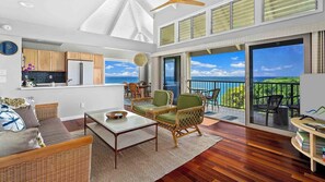 A spacious living area with a large sliding glass door leading to a balcony with a view of the ocean.