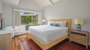 Habitación de hotel con una cama grande, lámparas de noche, un escritorio con computadora y vista a zonas verdes.