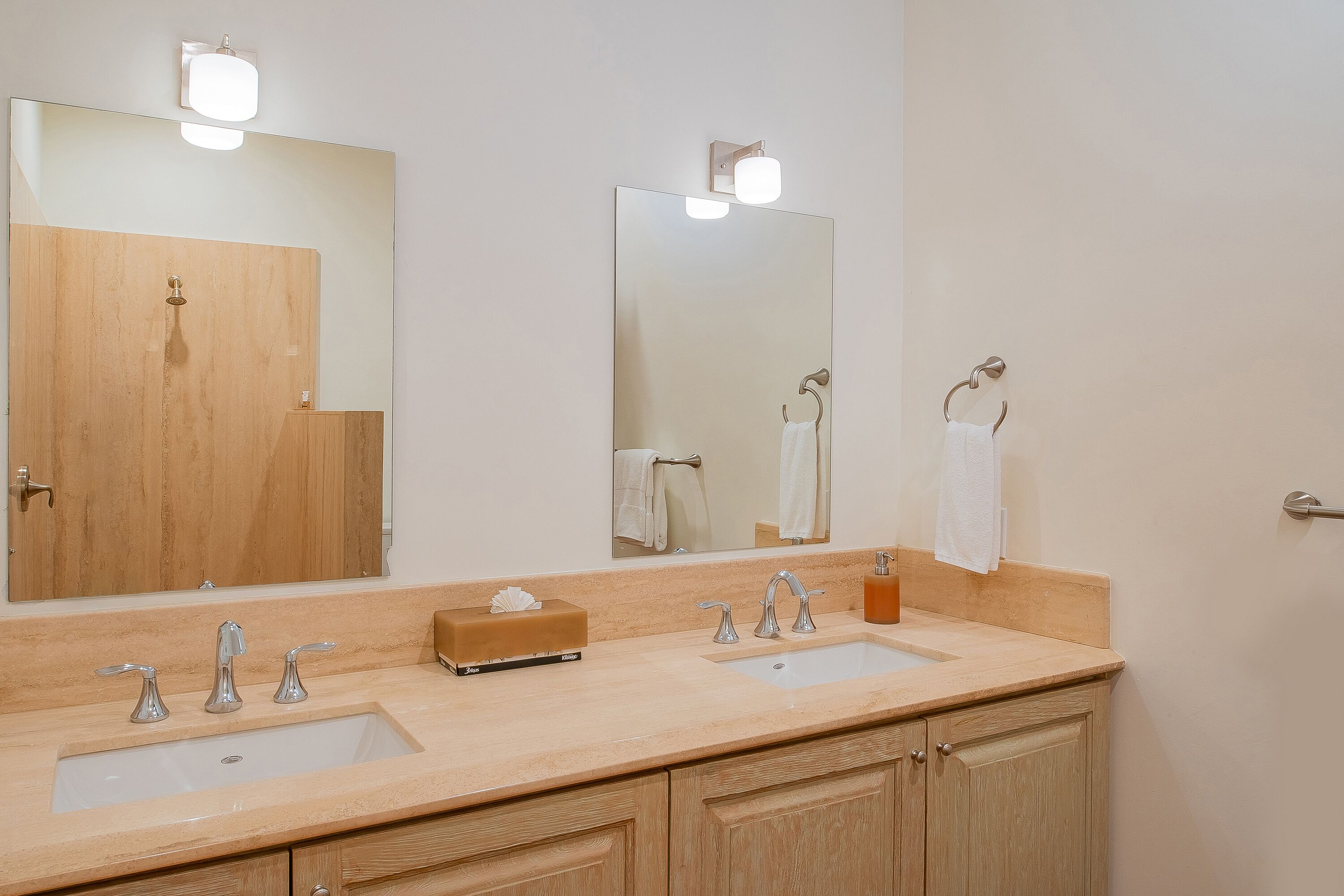 A bathroom with two sinks, a large mirror, and wooden cabinets.
