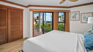 A bedroom with a large bed, a sliding glass door to a balcony, and wooden doors.