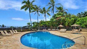 A swimming pool with lounge chairs and palm trees in the background.