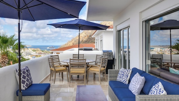 Ein Balkon mit Tisch, Stühlen, einer Couch und Sonnenschirmen.