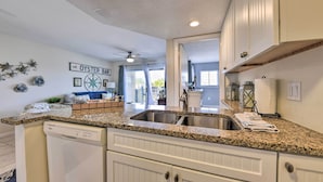 A kitchen with granite countertops, white cabinetry, and a visible dishwasher. - Ocean-View Fernandina Condo w/ Pool, Beach Access! (Fernandina Beach)