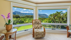 Una habitación con un amplio ventanal que ofrece vistas a un paisaje exuberante y montañas.