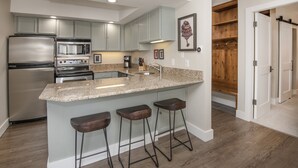 A modern kitchen with a central island, stainless steel appliances, and wooden cabinetry. - Fully remodeled with AC, steps from Gondola | W203 (Vail)