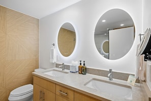A modern bathroom with two sinks, a toilet, and wooden paneling.