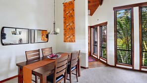 A dining area with a wooden table, chairs, and a decorative wall hanging.
