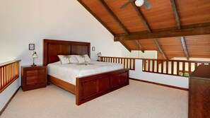 A bedroom with a wooden bed, nightstands, a ceiling fan, and a view of the outside through a window.