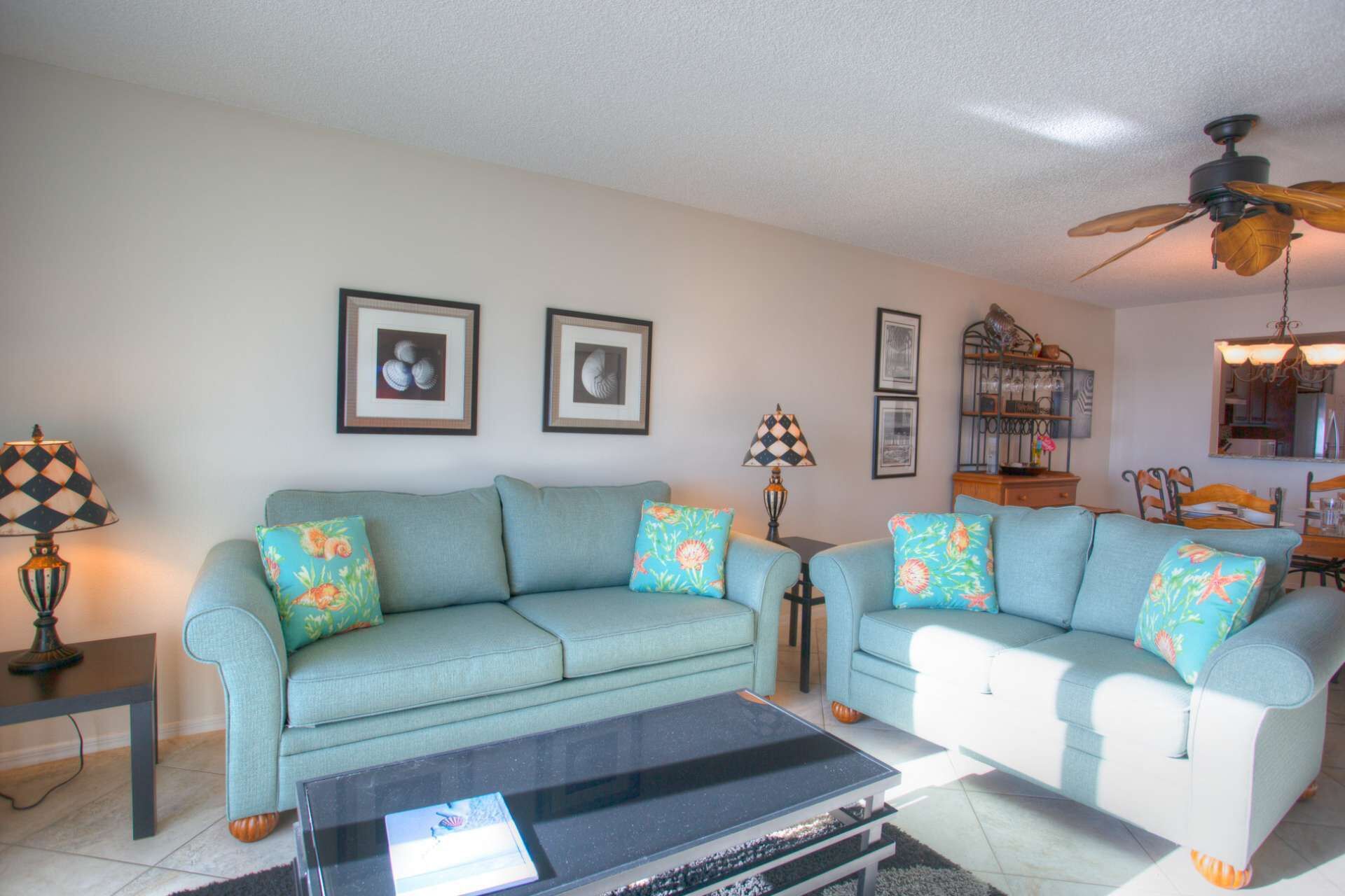 A living room with two light blue sofas, a coffee table, and framed pictures on the wall.