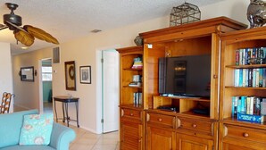 A living room with a sofa, wooden entertainment center, and a ceiling fan.