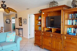 A living room with a sofa, wooden entertainment center, and a ceiling fan.