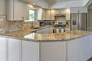 Una cocina moderna con encimeras de granito, electrodomésticos de acero inoxidable y armarios blancos.
